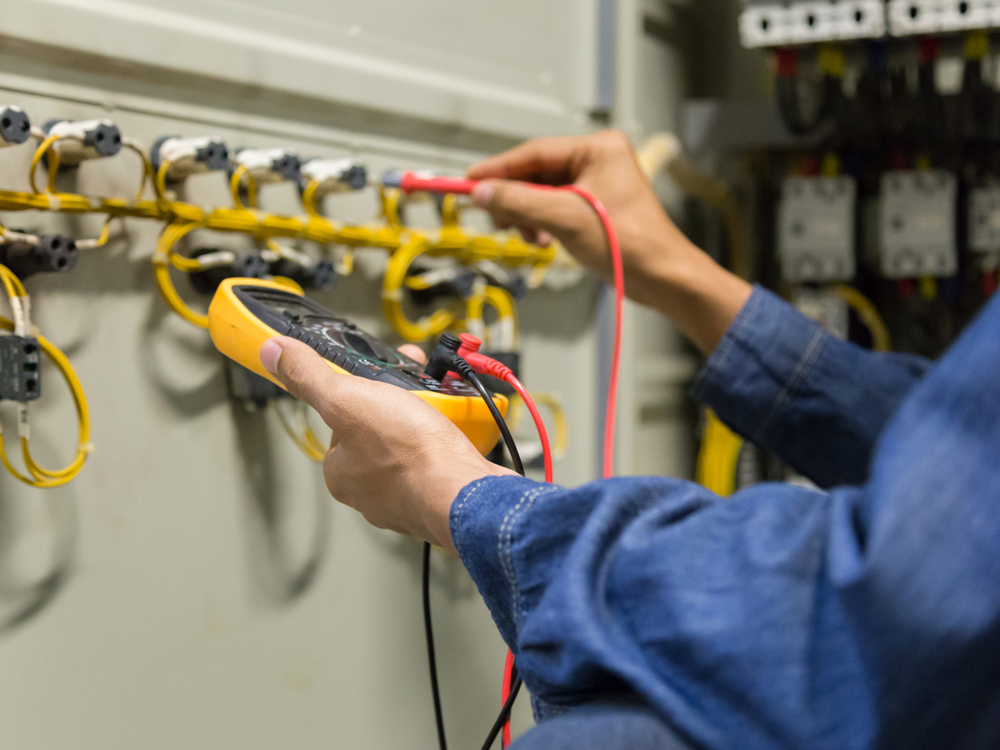 A person checks an electrical system using a multimeter, ensuring accurate readings for safety and functionality.